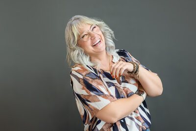 headshot of a woman in a patterned shirt laughing