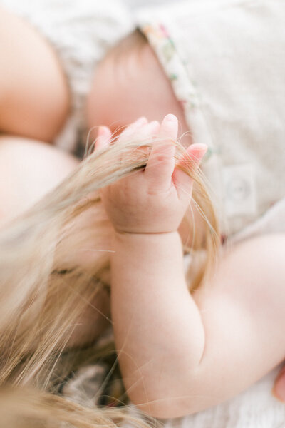 baby's hand in mothers hair while nursing by Orlando baby photographer
