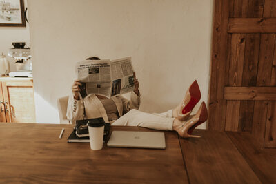 Career coach with feet on desk reading newspaper
