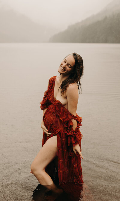 Side profile of a pregnant woman with flowing blonde waves, wearing a delicate body chain, during a professional maternity shoot by a photographer in Mullingar, Ireland.