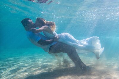 A bride and groom kiss underwater on Maui