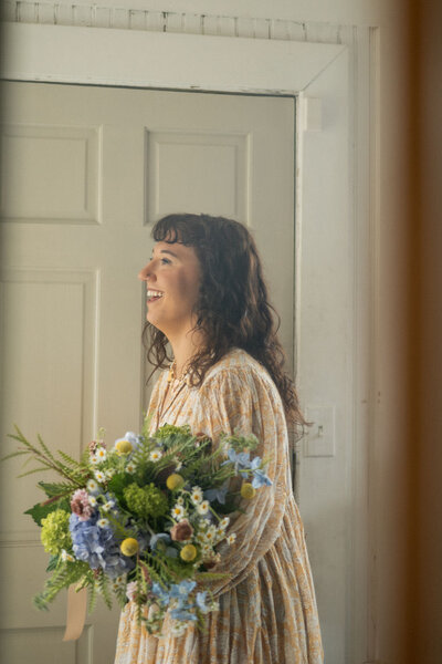 Pittsburgh wedding florist holding large bouquet in front of a door