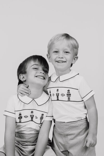 Black and white studio portrait of two little boys in christmas outfits
