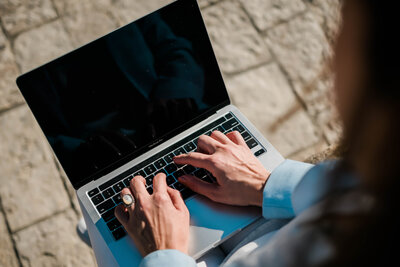 Concept of digital CFO illustrated as female hands working on a laptop outside in the sun, on a stone-cobbled street