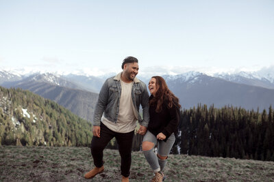 couple holding hands laughing by mountain range