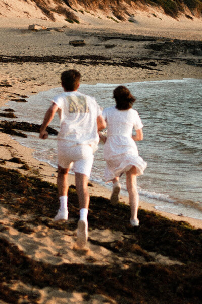 Grainy shot of couple running on the beach away from the camera