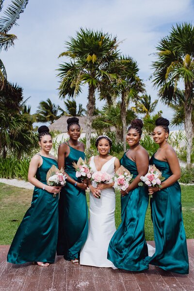 bridesmaids in teal dresses in front of beach at destination wedding
