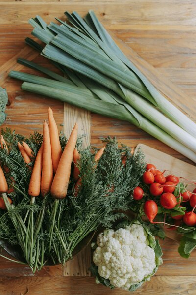 A table displaying various fresh vegetables alongside a wooden cutting board, emphasizing healthy eating for nutritional counseling.
