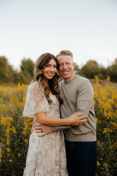 woman and man embracing in field pregnant belly