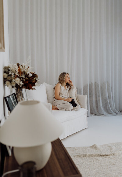A beautiful portrait of lucy jane photography a professional photographer in christchurch, she is sitting on her sofa in her beautiful newborn photoshoot