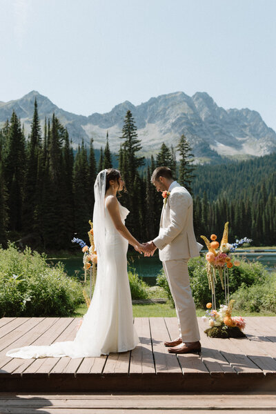Bride and groom hold hands at alter during their alberta wedding