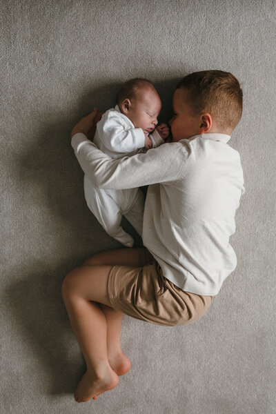 Newborn baby with his big brother both curled into foetal position