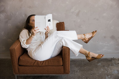 A woman holding a drink while reading a book. Showing that with anxiety therapy in Manhattan you can calm the inner chaos. An anxiety therapist can help you learn to relax and enjoy every day.