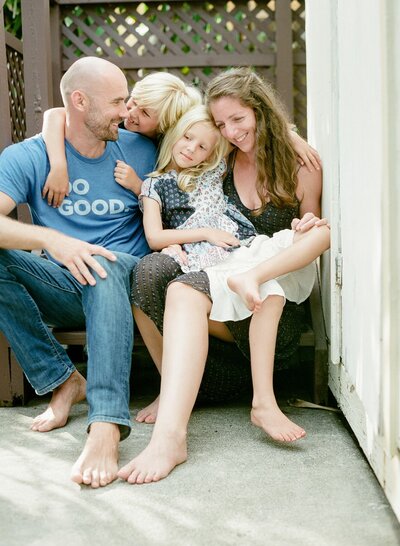 A woman and a man sit on steps with their two children, smiling.