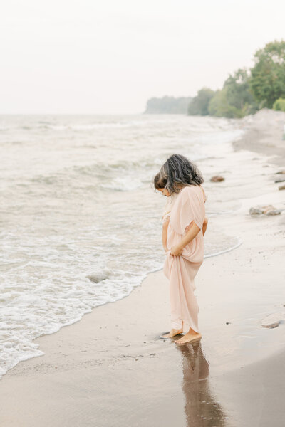 Mom in peach dress holding daughter at the beach by Toronto Newborn Photographer