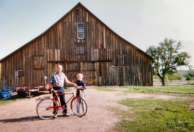 grandfather and girl standing by barn