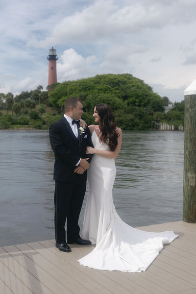 Bride and groom standing on a pier by a lake
