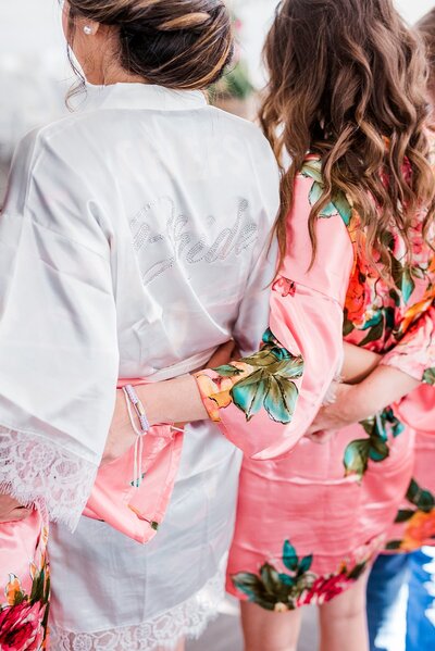 Detail photo of bride and bridesmaid holding Anemone bouquets with heavy greenery and white roses