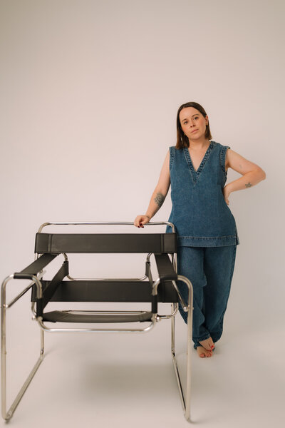 Liv Rollings standing by tall mirror and rust colored couch