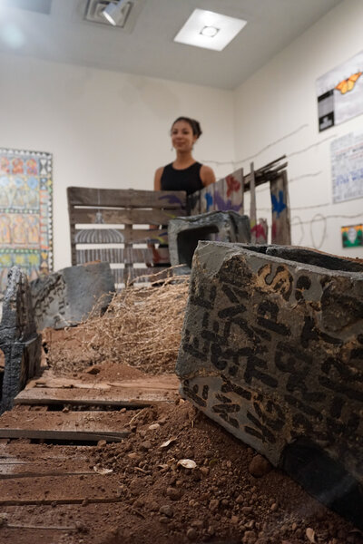 A cinder block that was hand made out of clay is decorated with underglaze to resemble graffiti and various other imagery