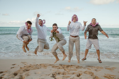 Andy and his groomsmen jumping on the beach