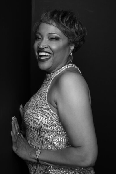 African American female woman in a silver dress poses on a black background for a black and white monochromatic beauty portrait at Janel Lee Photography studios in Cincinnati Ohio