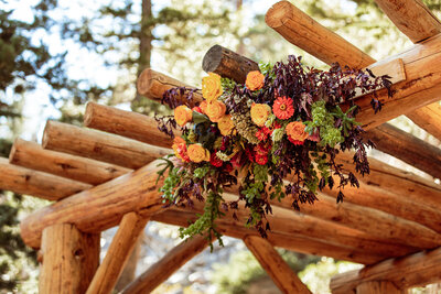 Fall flowers are displayed on wedding arch on mountain top wedding ceremony.