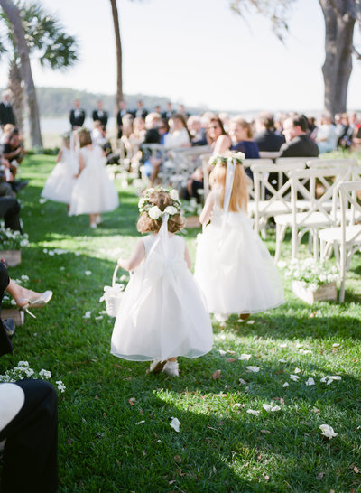 flower girls walking down the aisle  at a waterfront venue