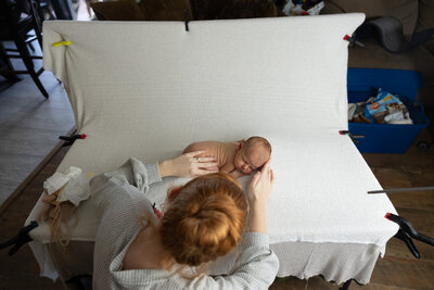 A newborn photographer poses a baby in a St. Louis photography studio.