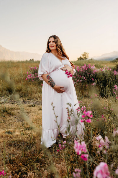 An expecting Mom is photographed cradling her maternity bump in a field of wildflowers.