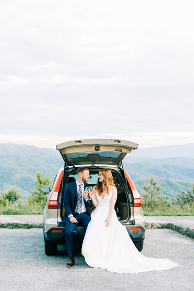 Couple smiling at eachother sitting in back of car overlooking mountain winx photo tennessee wedding photographer