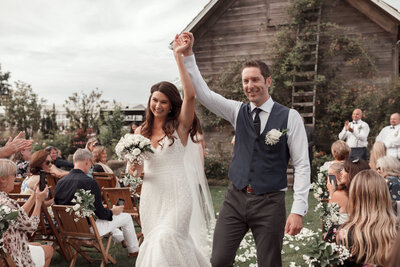 bride and groom holding hands walking down isle