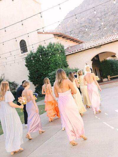angled photo of colorful bridesmaids walking out of a church wedding
