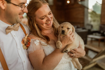 A bride and groom holding a puppy