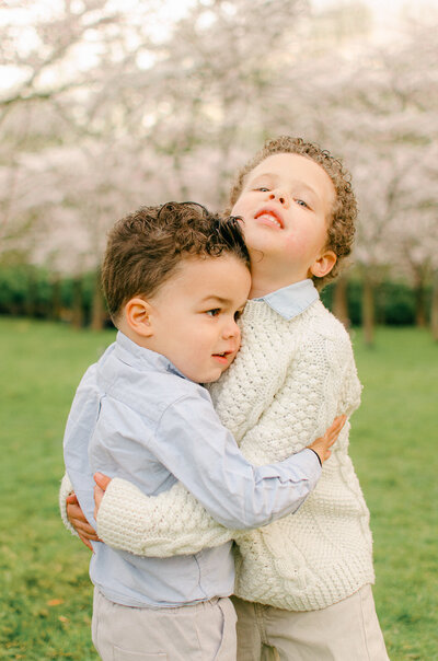 Brothers hug during a family cherry blossom photoshoot in the Bloesempark in Amsterdam.