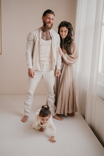Deze afbeelding toont een ongedwongen familieshoot waarin een gezin zich volledig laat gaan in een natuurlijke omgeving. De sfeer is ontspannen en speels, met spontane lachende gezichten en liefdevolle interacties die de sterke band binnen het gezin weerspiegelen. Deze fotoshoot legt niet alleen mooie beelden vast, maar ook de pure emoties en het plezier van het samenzijn, wat zorgt voor tijdloze herinneringen
