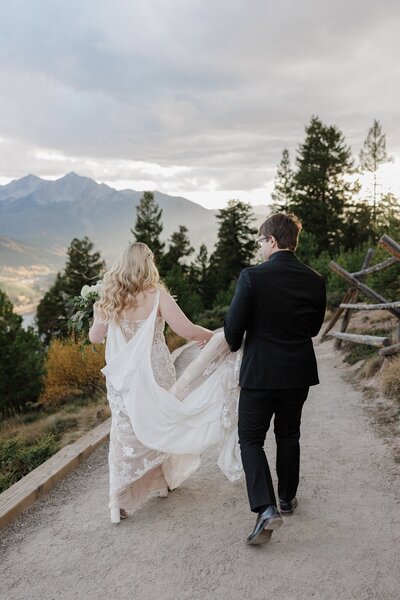 Bride and groom hike trail surrounded by fall colors during Colorado elopement.