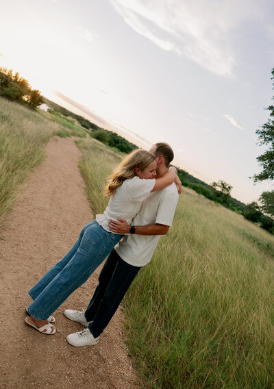 Engaged couples sharing an intimate moment in a wide-open field in Texas at sunset