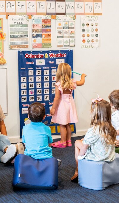 Children learning from a classroom calendar at The Nest, a natural learning center in Surf City, NC
