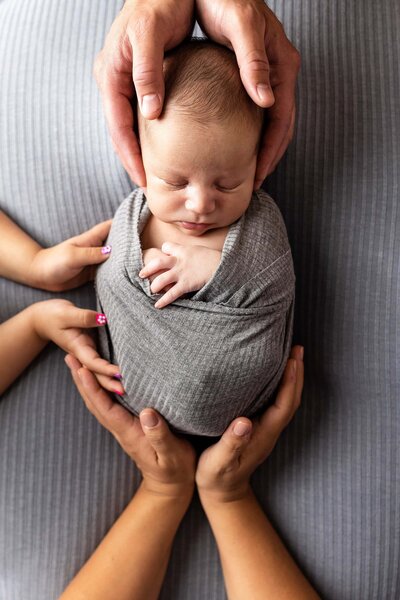 Newborn baby in grey swaddle