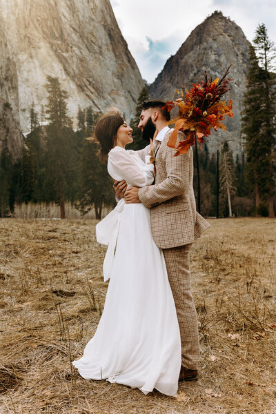 bride and groom embracing with boho bouquet in yosemite  national park california
