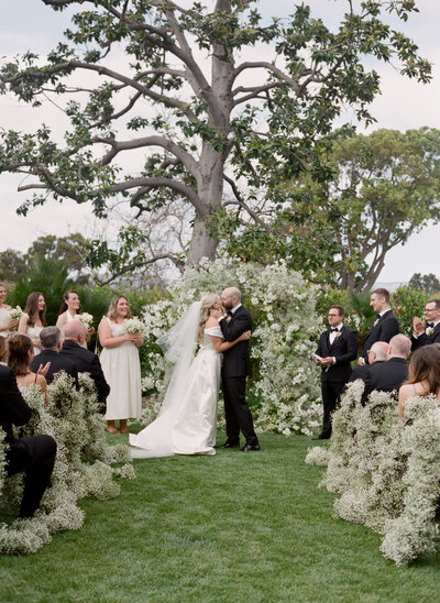 groom in tuxedo and bride in white wedding gown kissing
