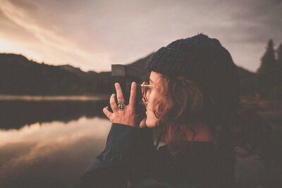 Female looking through a camera in nature, finding healing through trauma therapy.