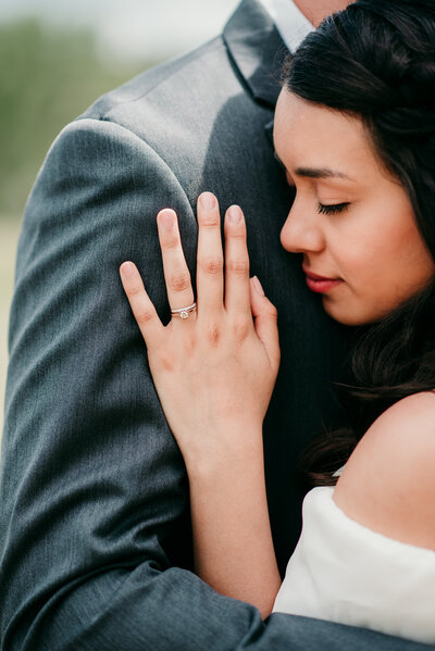 engagement ring detail shot with bride embracing her groom and holing her hand on his chest with rocky mountain national park wedding