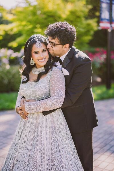 Indian groom kissing bride on the cheek at their wedding reception at jericho terrace in long island