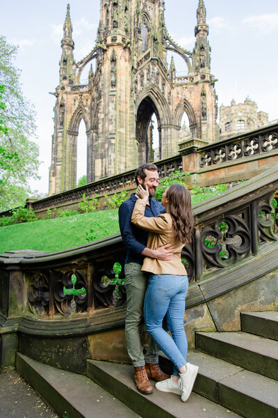 engaged couple smile on park staircase