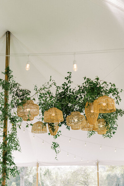 foliage draped on rustic wicker lanterns hanging in a tent