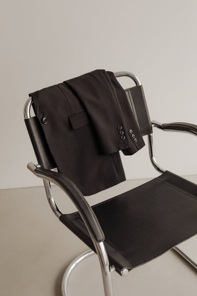 Chic minimal black jacket hanging on back of chair