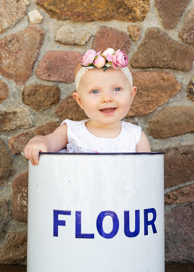 baby posing in old flour tin