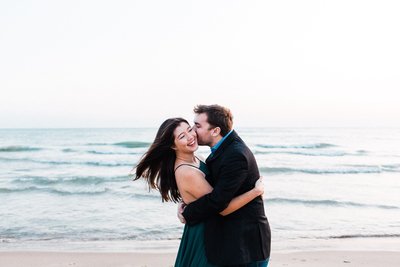 Couple at Washington beachfront with husband kissing cheek